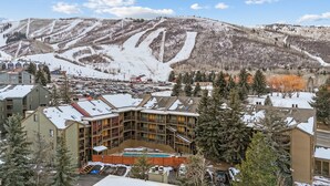 Une station de ski dotée d’un grand parking, d’un bâtiment à plusieurs étages et offrant une vue sur un paysage montagneux.