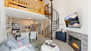 Un salon moderne avec une cheminée, un coin repas et une cuisine.