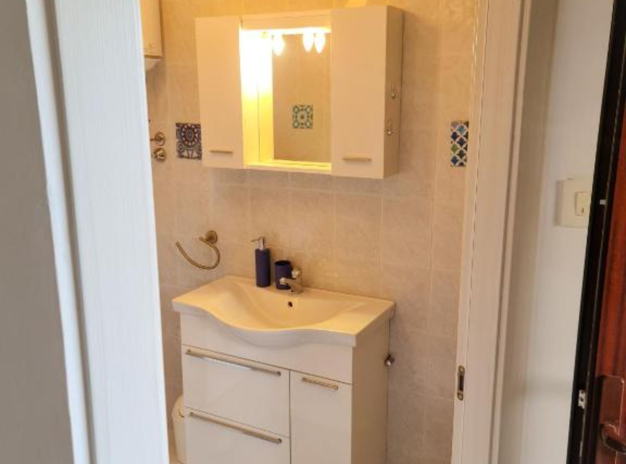 A bathroom with a white sink, a mirror above it, and a towel rack.