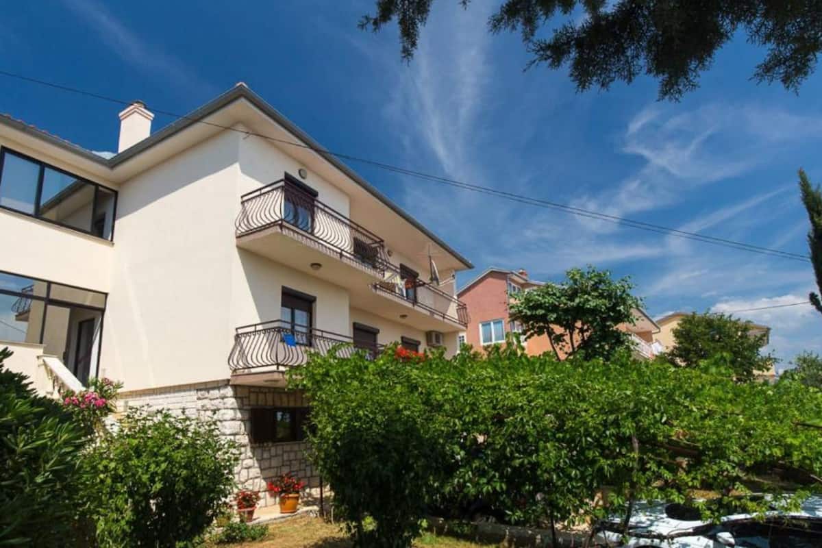 A two-story building with balconies, a stone foundation, and a clear blue sky.
