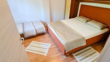 Um quarto pequeno e acolhedor com uma cama de casal, uma mesinha de cabeceira e uma prateleira na parede.