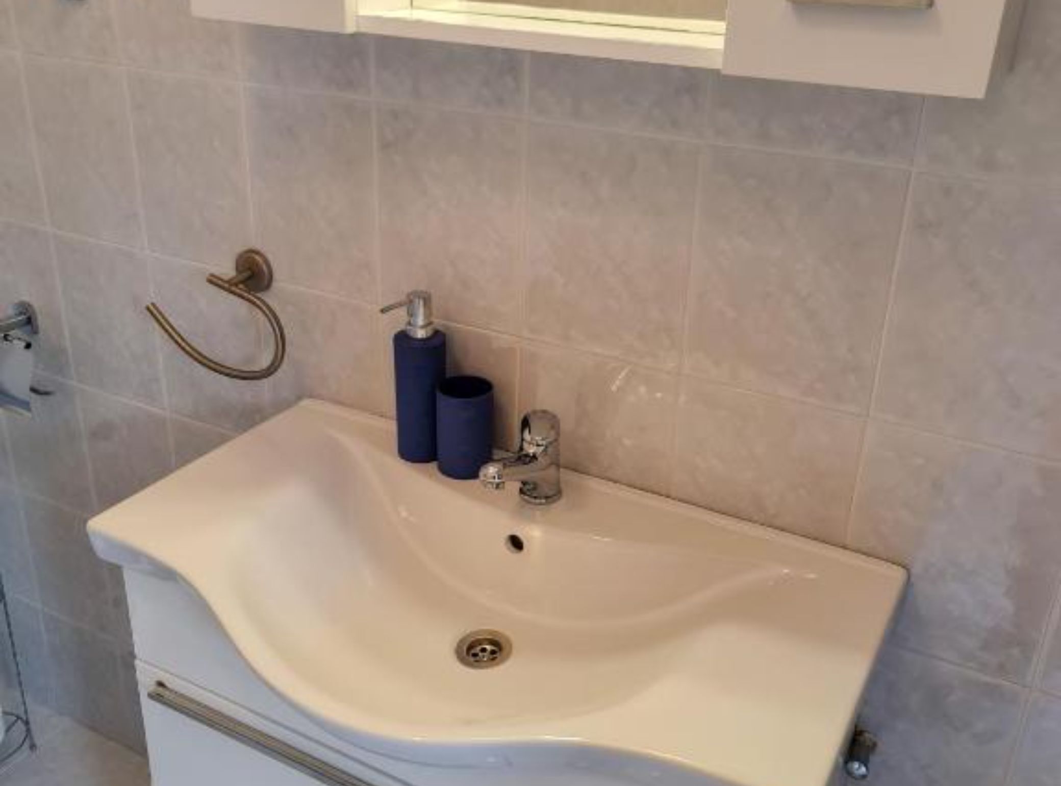 A bathroom with a white sink, a towel rack, and a mirror.