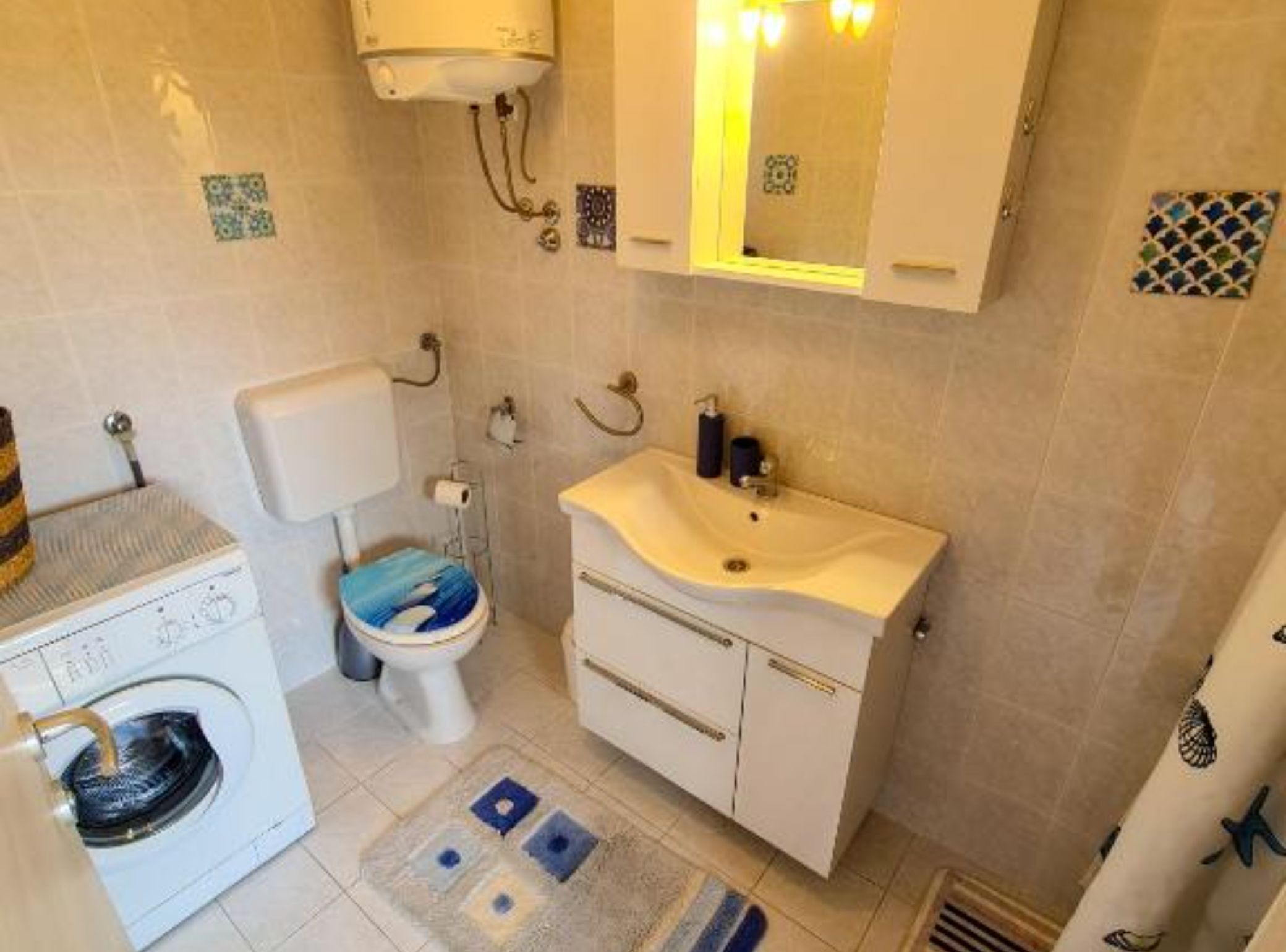 Un bagno compatto con il water, lavandino e lavatrice.