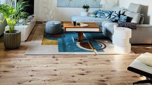A modern living room with a world map on the wall, a sofa, a coffee table, and a potted plant.