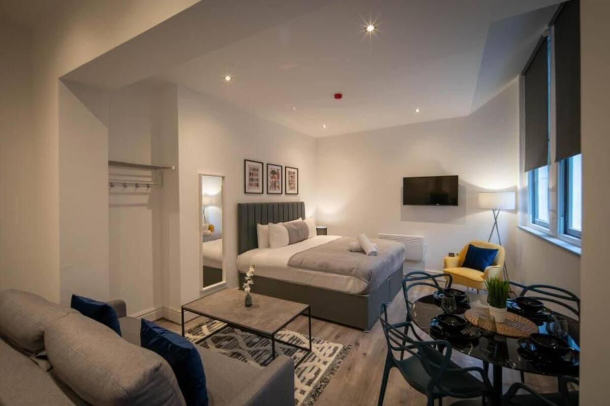 A modern bedroom with a bed, bedside table, and a TV mounted on the wall.