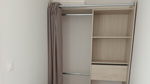 A room with a green sofa, a wooden floor, and a built-in closet with shelves.
