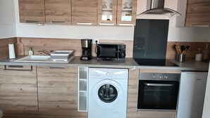 A modern kitchen with wooden cabinets, a coffee maker, a microwave, a dishwasher, and an oven.