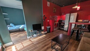 A modern living space with a sofa, a TV, a kitchen area, and a dining table. - Downtown Cottage (Orlando)