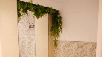 A bathroom with a toilet, a washing machine, and a shower area with a green plant decoration.
