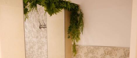 A bathroom with a toilet, a washing machine, and a shower area with a green plant decoration.