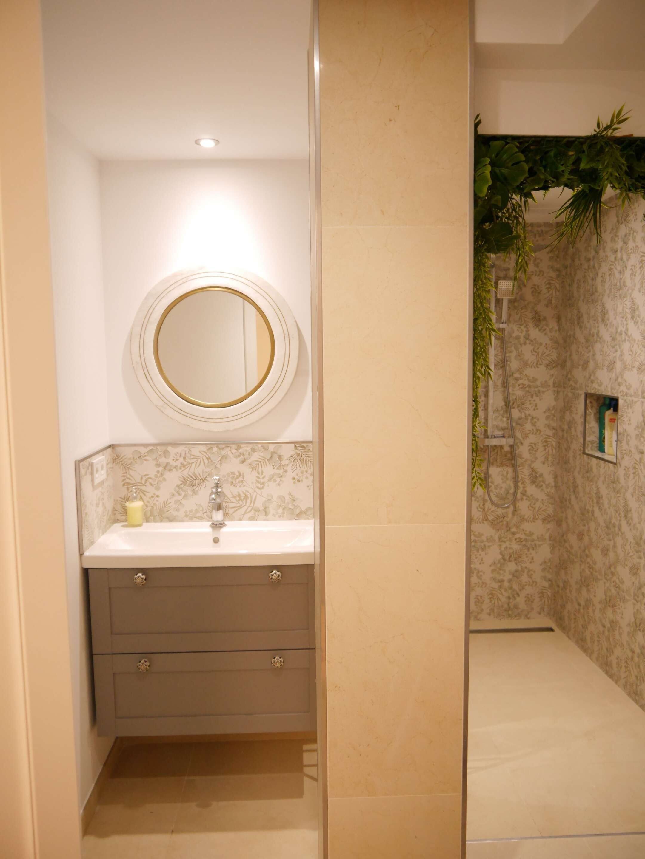 A bathroom with a round mirror, a sink, and a shower area.
