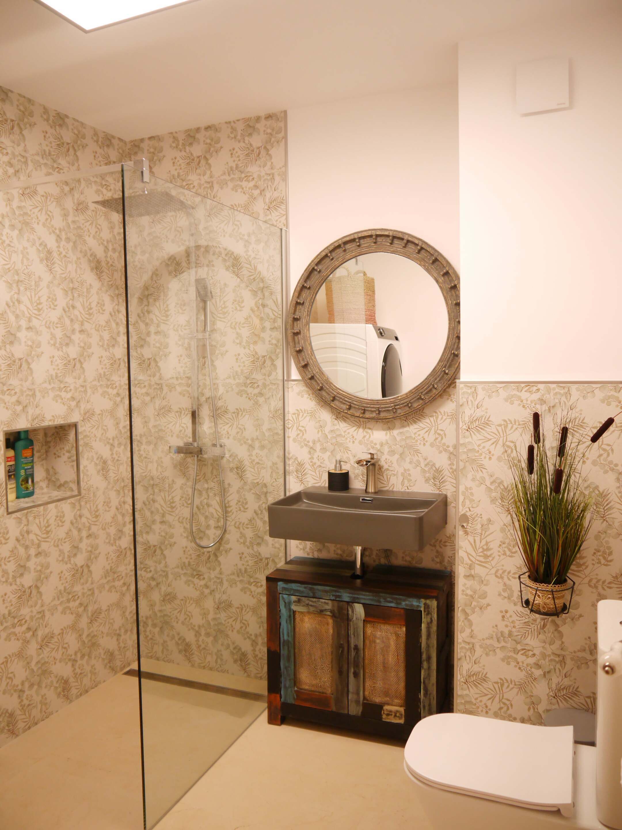 A bathroom with a shower, a sink with a mirror, and a toilet.