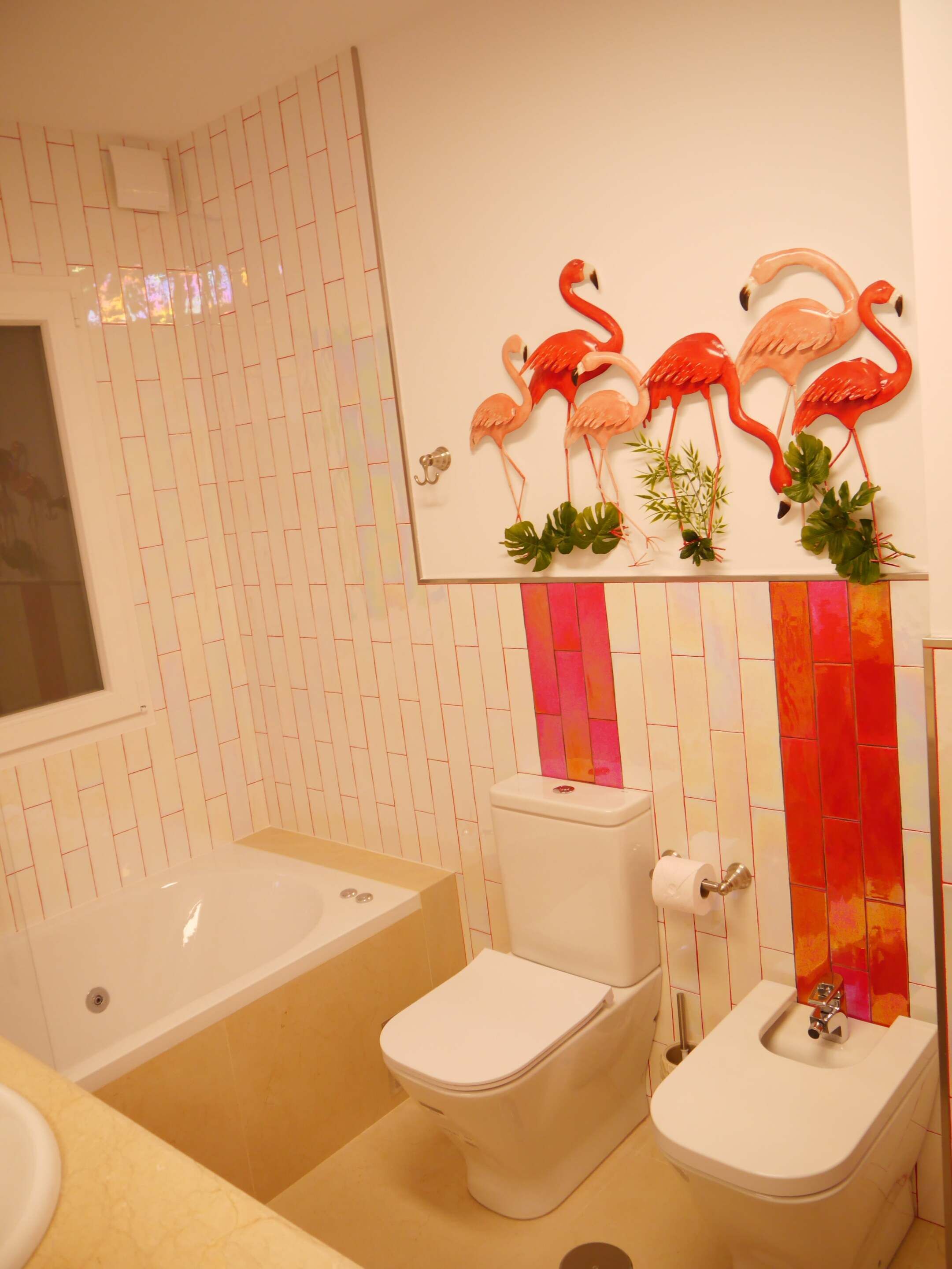 A bathroom with a bathtub, toilet, and bidet. There is a wall-mounted mirror above the toilet.