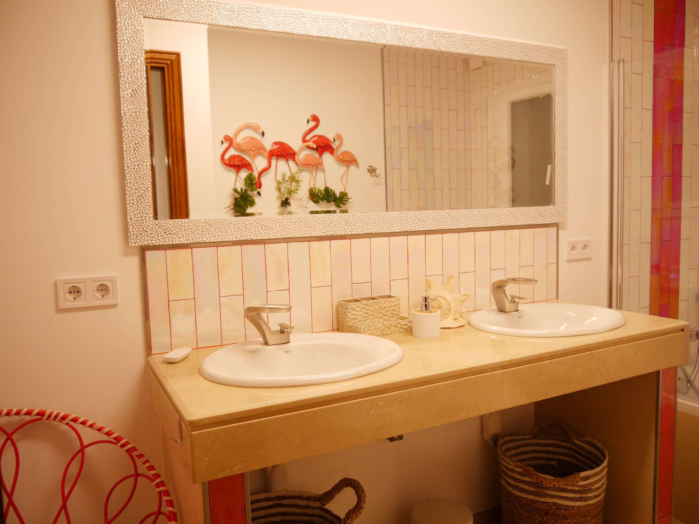 Ein Badezimmer mit zwei Waschbecken, einem Spiegel und einer gefliesten Rückwand.