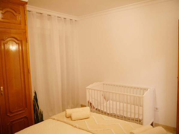 A baby room with a crib, a wooden door, and a curtain.