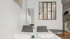 A modern bedroom with a large bed, two pillows, a bedside table, and a small table.