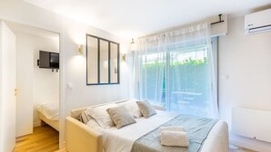 Un dormitorio con cama, televisor y ventana con cortinas.