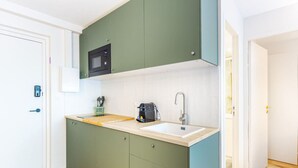 Una cocina pequeña equipada con microondas, lavaplatos y cafetera.