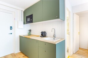 A compact kitchen with a microwave, sink, and coffee maker.