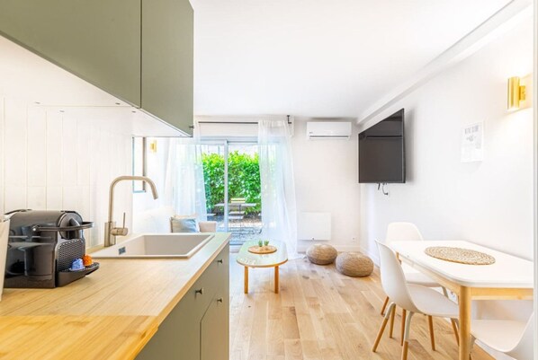 Una cocina moderna con una cafetera, un lavamanos y una zona de comedor con mesa y sillas.