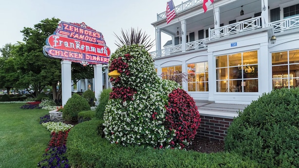 Un bâtiment sur lequel est apposée une grande enseigne indiquant la présence d’un restaurant, entouré de jardins bien entretenus et surmonté d’un drapeau.