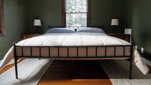Une chambre à coucher comprenant un lit, deux tables de chevet avec des lampes, une fenêtre et un élément décoratif mural.