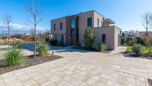 Een modern huis met twee verdiepingen, een verharde oprit en een aangelegde tuin.