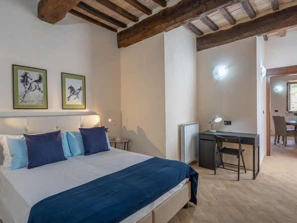 A bedroom with a bed, a desk, and a chair. There are two framed pictures on the wall. - Agriturismo Borgo Pulciano in Montone (Montone)