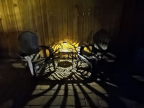 Un patio con una mesa, sillas, un farol y una valla de madera al fondo.