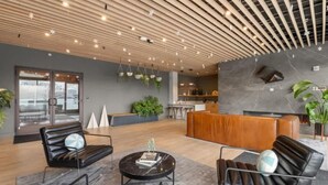 A modern lobby with leather sofas, a black coffee table, hanging plants, and a stone fireplace.