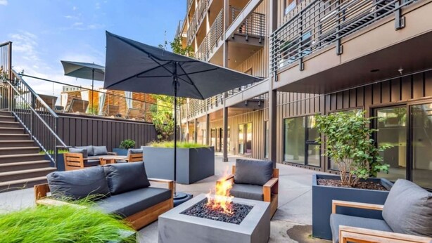 An outdoor seating area with a fire feature, outdoor furniture, and a staircase leading to an upper level.