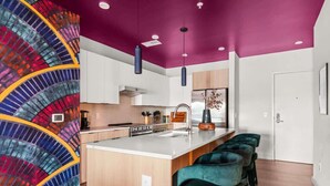 A modern kitchen with a central island, bar stools, and a colorful wall mural.