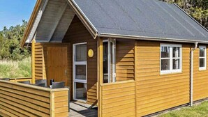 A wooden cabin with a porch, a door, and windows. - 6 Person Holiday Park Home in Skagen (Skagen)