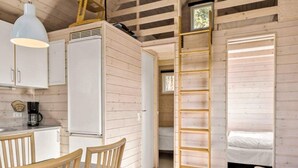 A compact cabin with a kitchenette, a dining area, a ladder to a loft, and a single bed. - 6 Person Holiday Park Home in Skagen (Skagen)