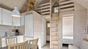 A compact, open-plan cabin with a kitchenette, dining area, and a loft bed. - 6 Person Holiday Park Home in Skagen (Skagen)