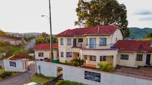 A multi-story residential building with a red-tiled roof, a balcony on the second floor, and a gated entrance. - THE HAVEN GUEST HOUSE THEMBELIHLE  (Mbabane)