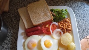 A white plate with toast, lettuce, beans, tomatoes, onions, eggs, and potatoes. - THE HAVEN GUEST HOUSE THEMBELIHLE  (Mbabane)