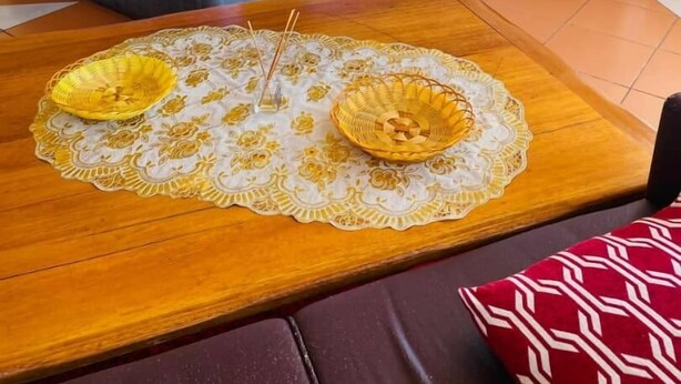 A hotel room with a bed, a bedside table, a lamp, a picture on the wall, and a wooden table with a placemat. - THE HAVEN GUEST HOUSE THEMBELIHLE  (Mbabane)