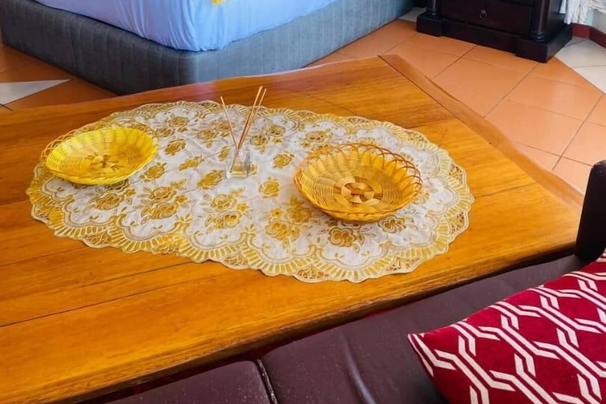 Et hotelværelse med en seng, et natbord, en lampe, et billede på væggen og et træbord med en pladsmat.