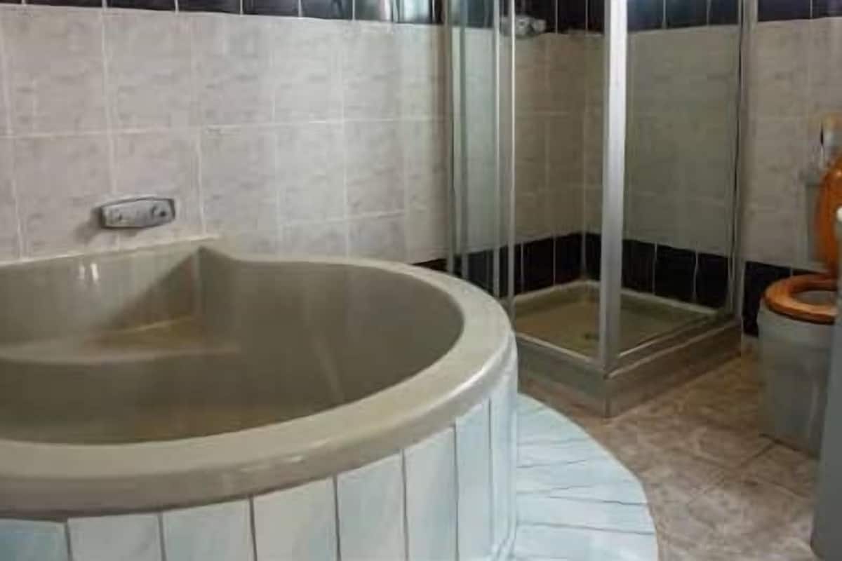 Et badeværelse med badekar, toilet og brusebad.