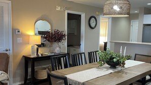 A dining area with a wooden table, chairs, and a hanging light fixture.