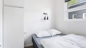 Une chambre à coucher avec un lit, une armoire et une fenêtre équipée de stores.