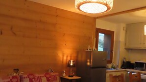 Una sala de estar acogedora con un sofá, una mesita, un refrigerador y una zona de cocina al fondo.
