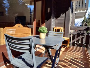 Eine Terrasse mit Tisch und Stühlen, einem Blumentopf und einem Holzzaun.