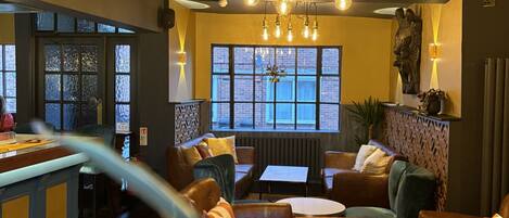 A cozy lounge area with plush seating, a bar, and large windows allowing natural light.