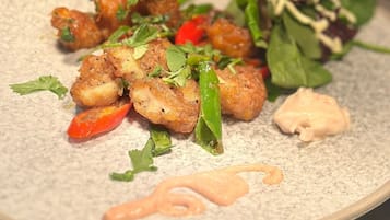 A plate of food with fried items, greens, and a sauce.