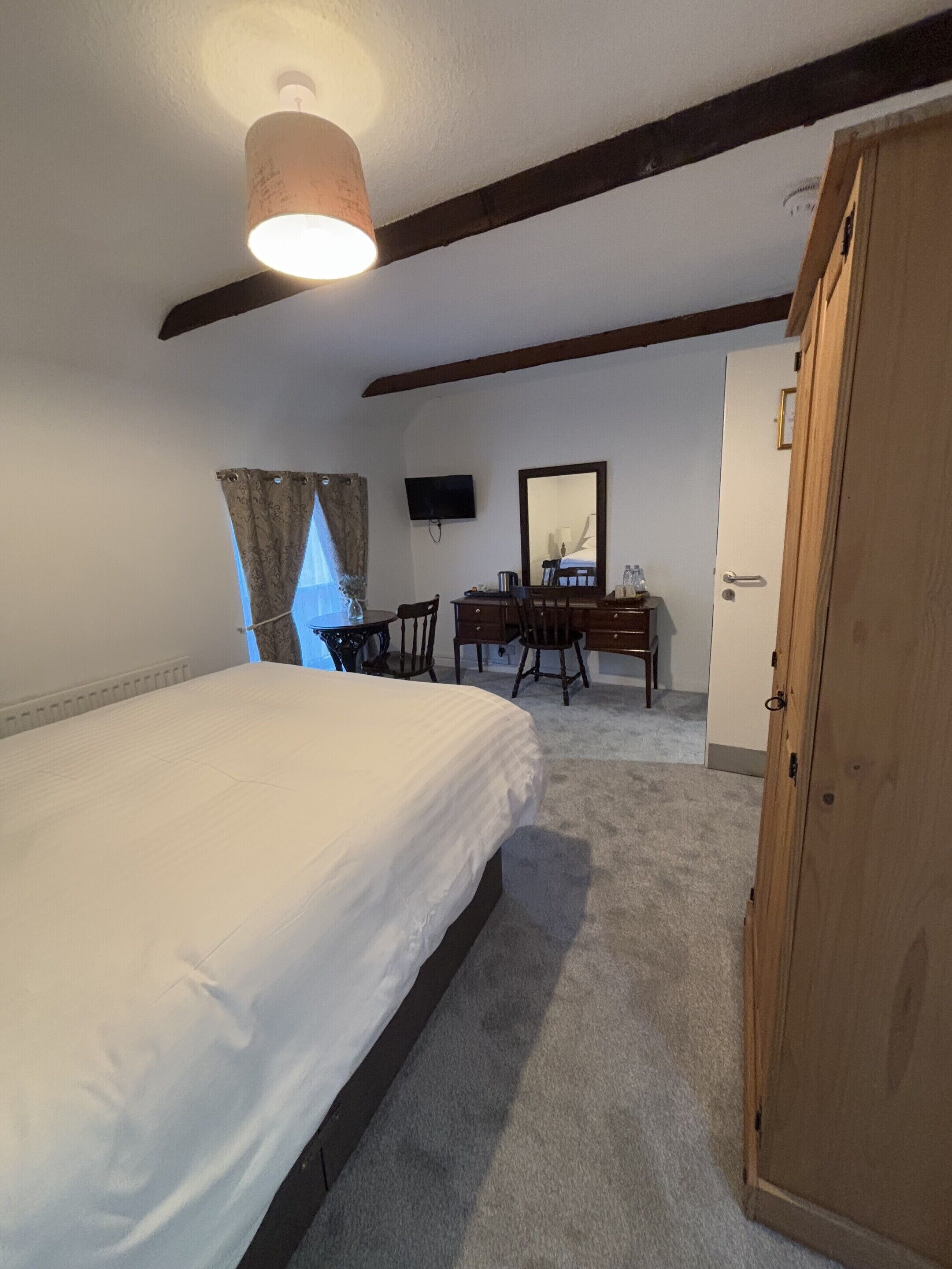 Un dormitorio con cama, escritorio, silla, televisor y armario.