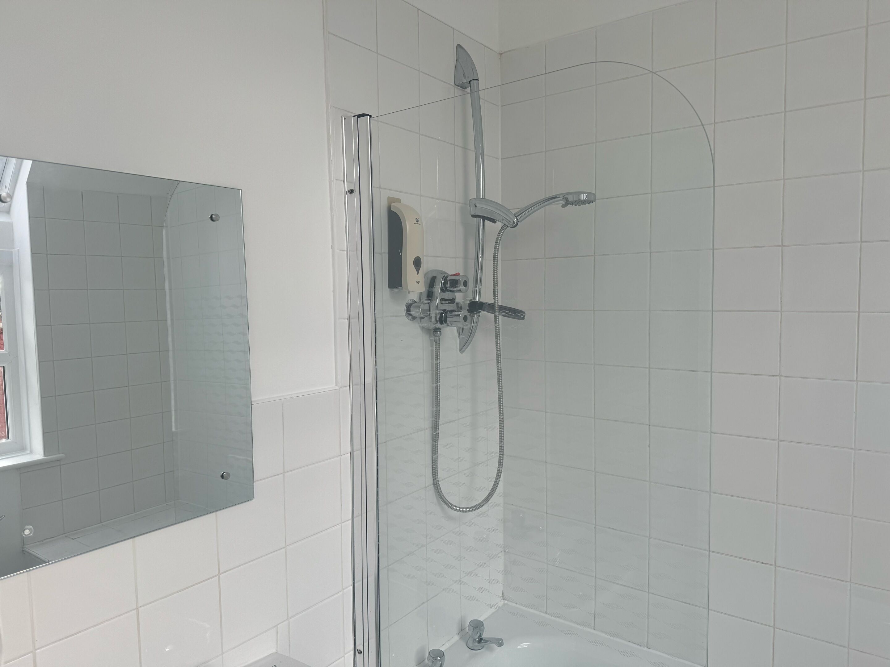 A modern bathroom with a glass-enclosed shower, a built-in sink, and a mirror.