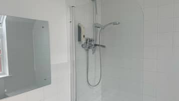 A modern bathroom with a glass-enclosed shower, a built-in sink, and a mirror.