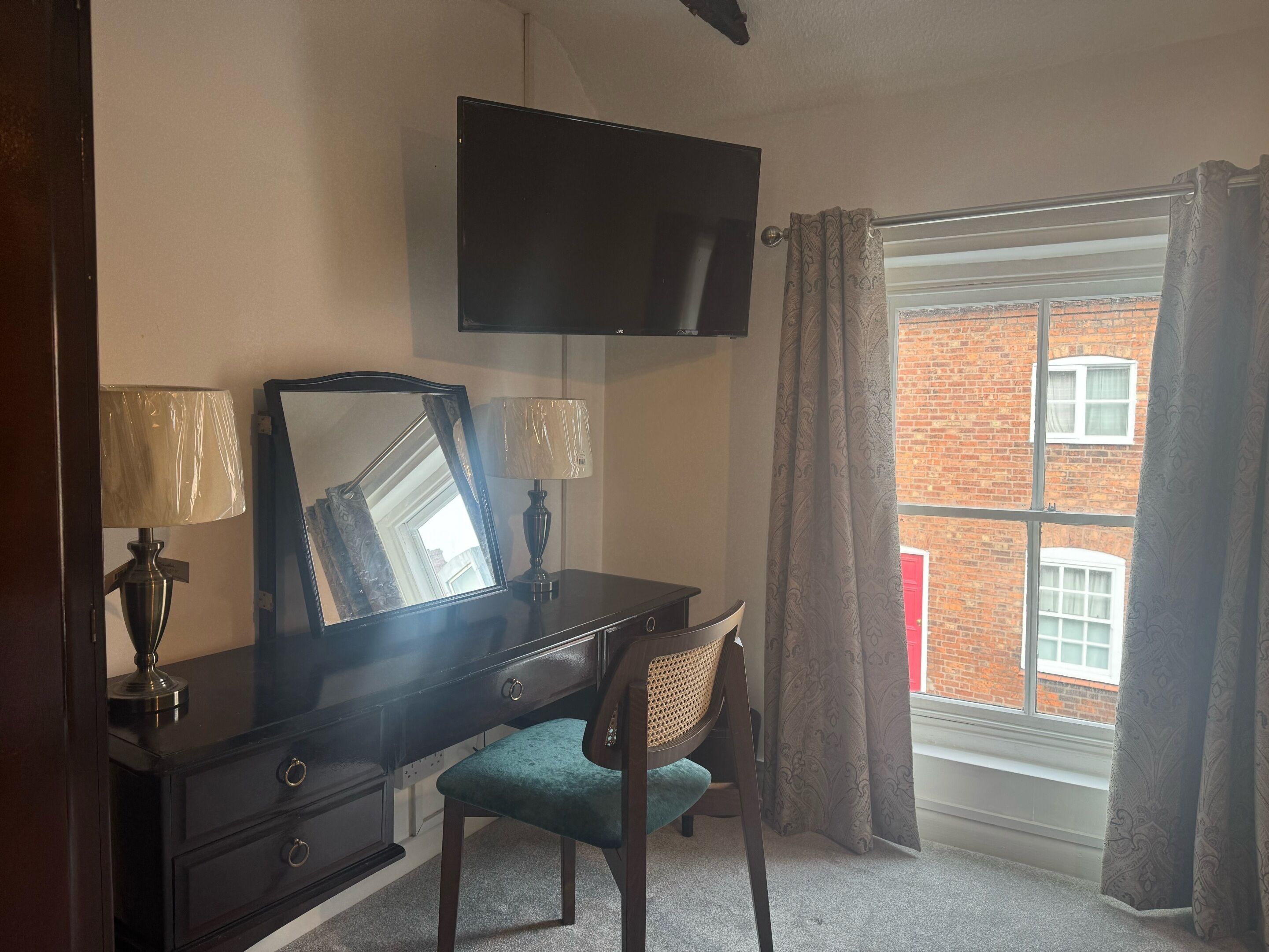 Una habitación con escritorio, silla y televisión instalada en la pared.